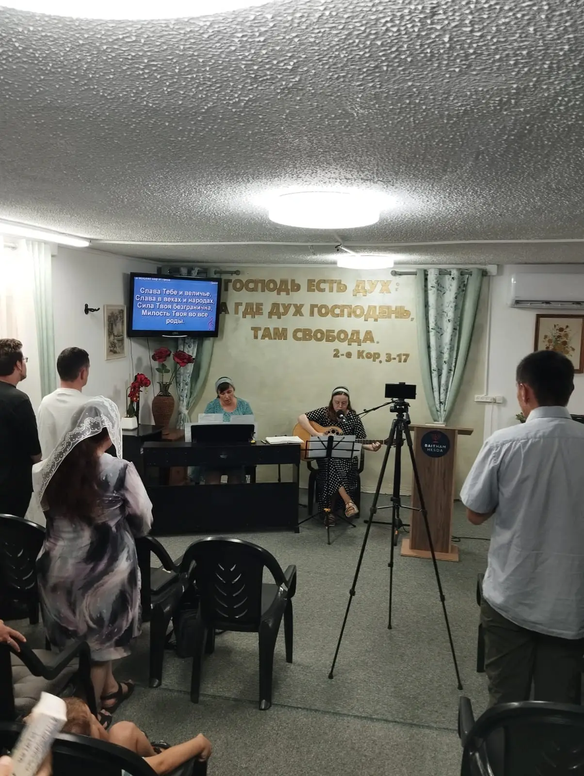 Two women play keyboard and guitar on stage before an audience during an Ashkelon family church visit.