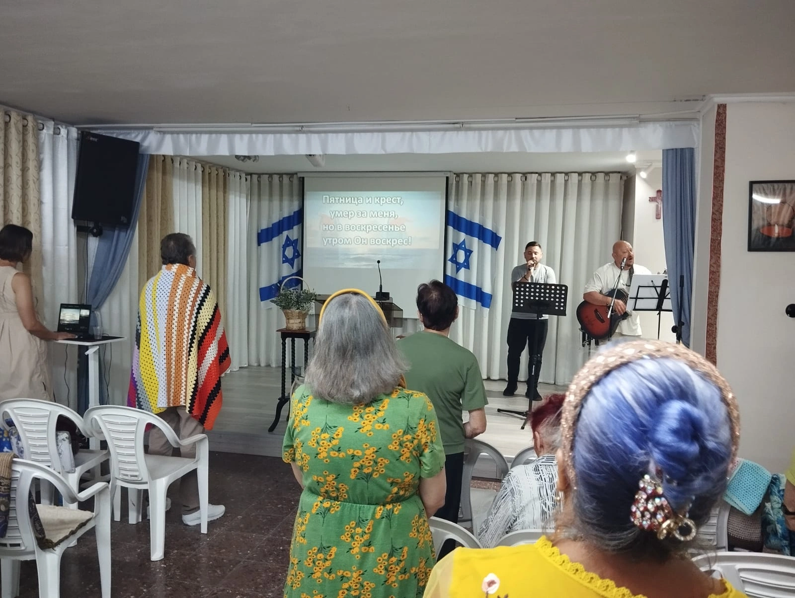 Worship leaders sing on stage with a guitar during our Akko church fellowship trip.
